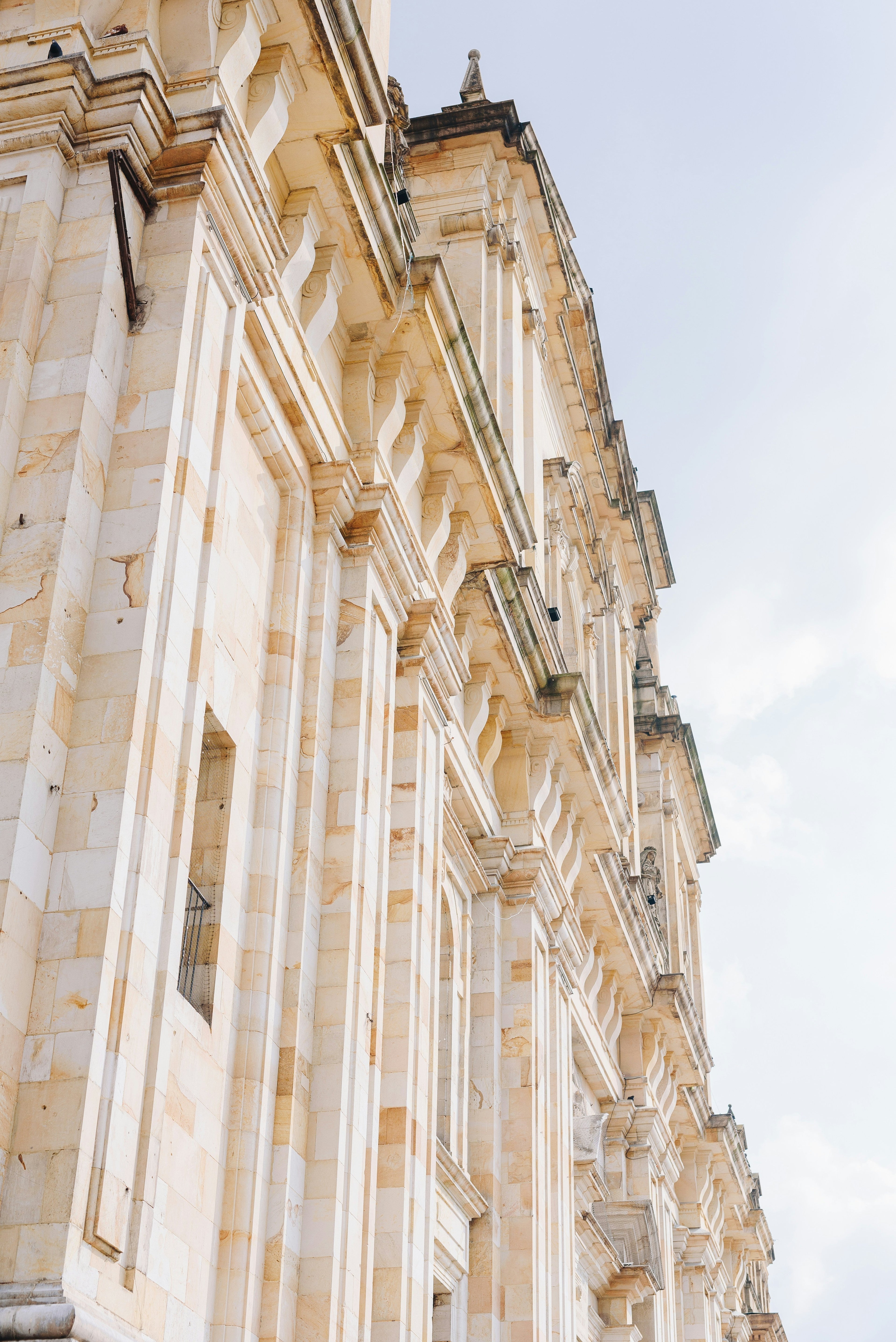a tall sandstone facade with clean, sharp lines rising into a clear blue sky, calm and majestic in its presence, suggesting quiet success and grounded strength.