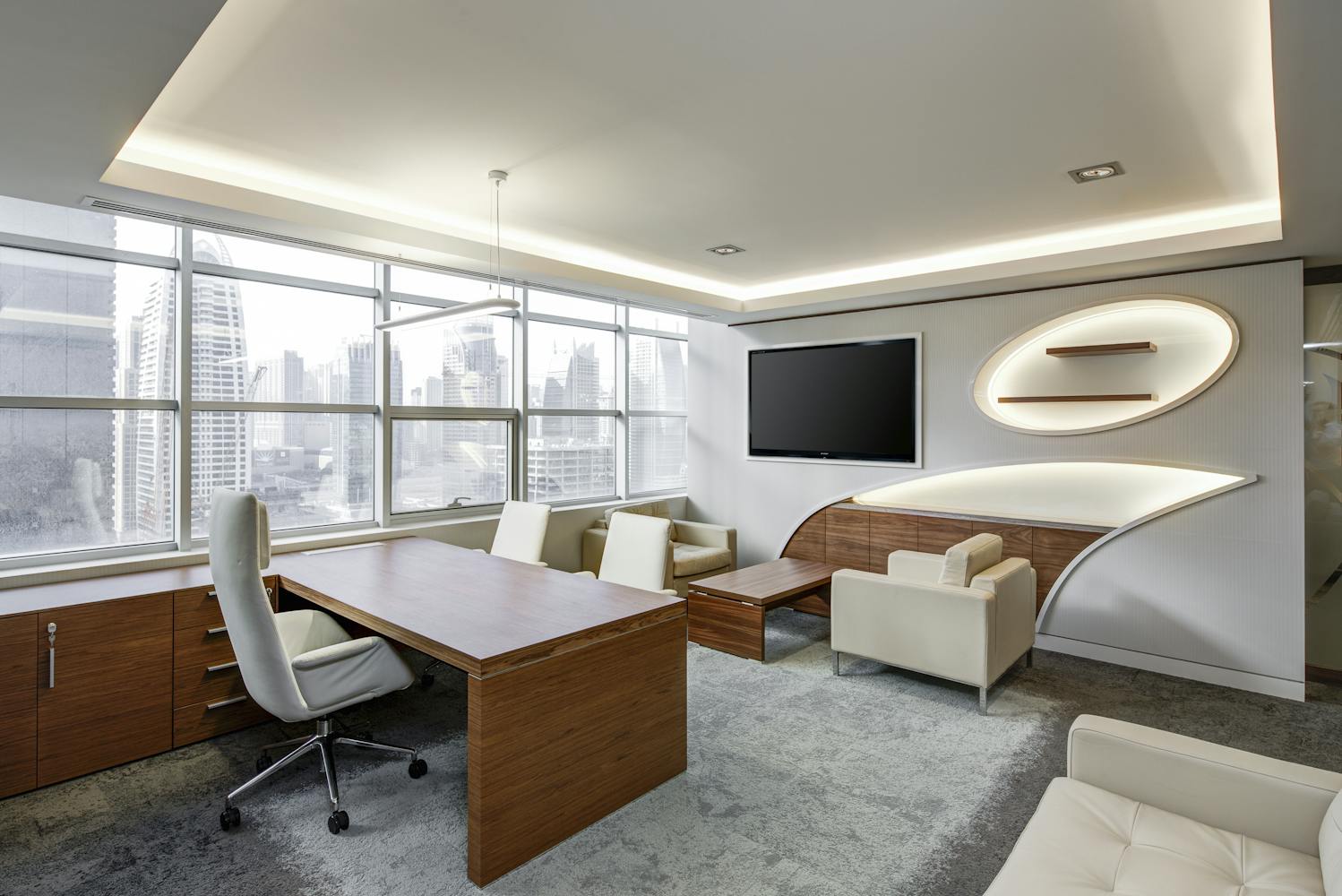 a modern executive office with a large minimalist desk, clean lines, comfortable chairs, and a wall‑mounted TV, designed in a bright, professional workspace style that suggests clarity, leadership, and contemporary corporate design.