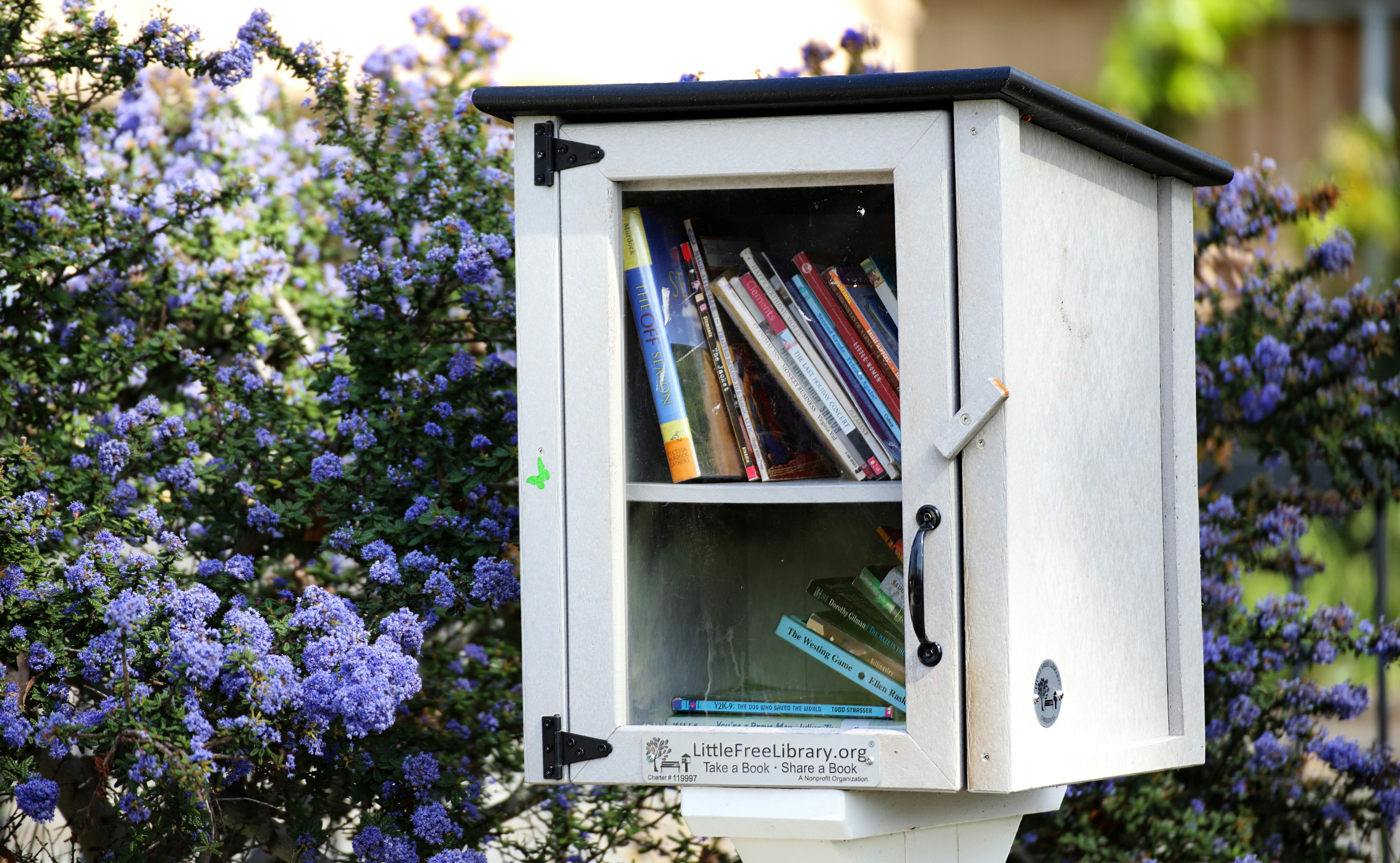 a small public book cabinet filled with used books, offering quiet exchange, shared knowledge and community warmth. the scene conveys generosity, friendliness and mindful leadership in symbolic form.