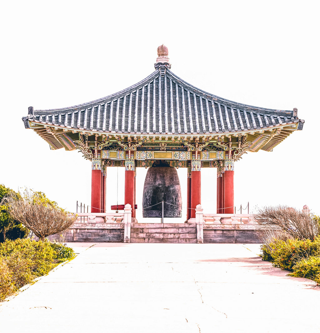 generosity: an over‑roofed korean friendship bell standing in soft daylight, symbolizing calm connection and balanced generosity.