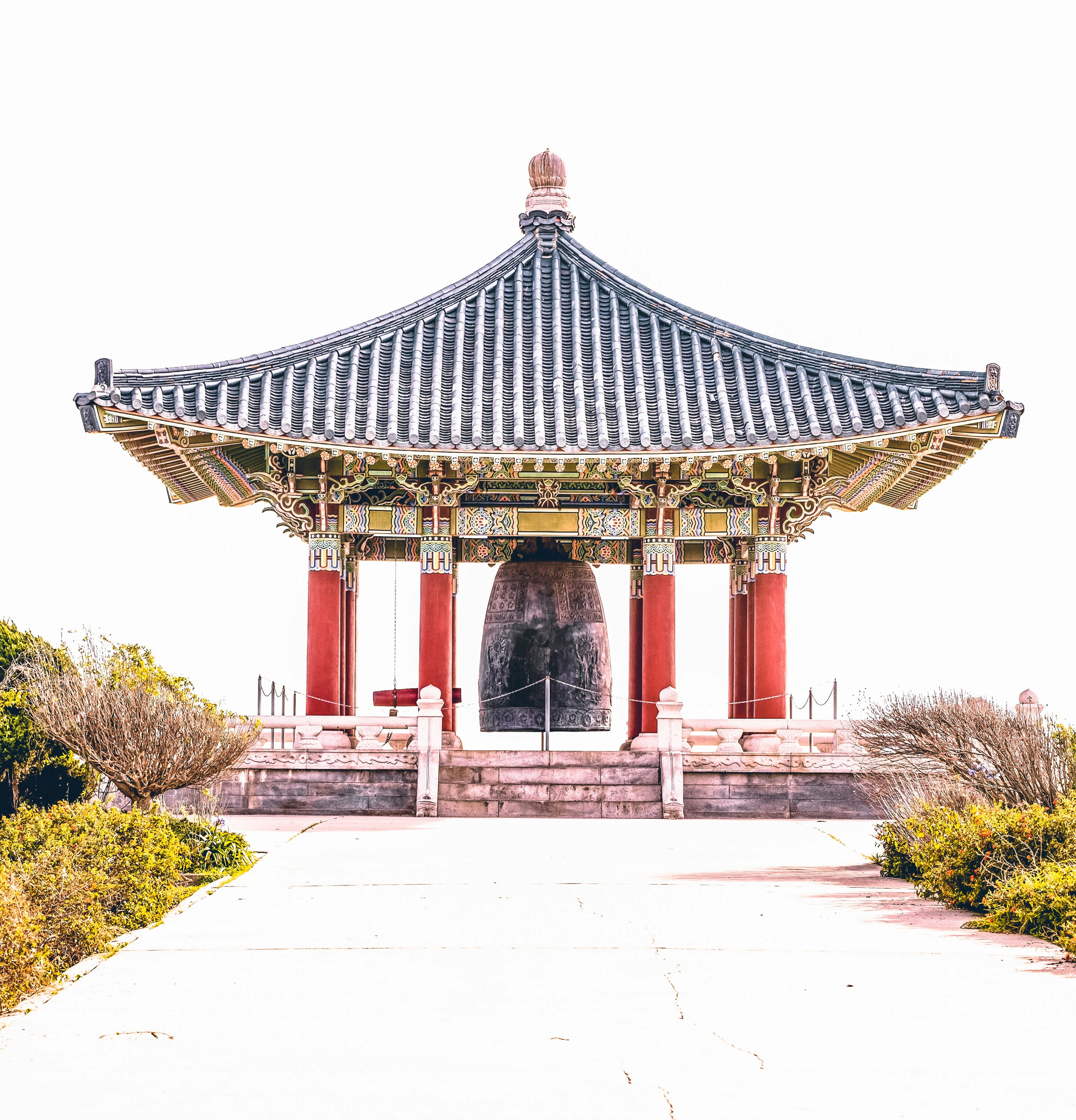 generosity: an over‑roofed korean friendship bell standing in soft daylight, symbolizing calm connection and balanced generosity.