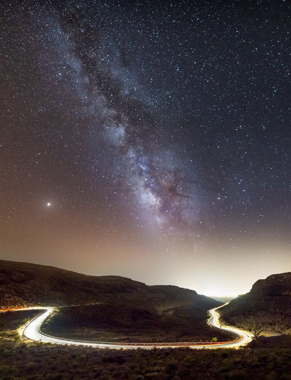a starry night sky over a winding road in a mountainous landscape, a quiet scene of darkness, depth, and natural light — a calm, expansive setting symbolizing reflection, direction, and inner clarity.