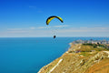 a paraglider flying over a coastal landscape with blue sky and ocean, capturing freedom, height, and calm movement above the shoreline — a bright, expansive outdoor scene ideal for travel, adventure, and coastal inspiration.