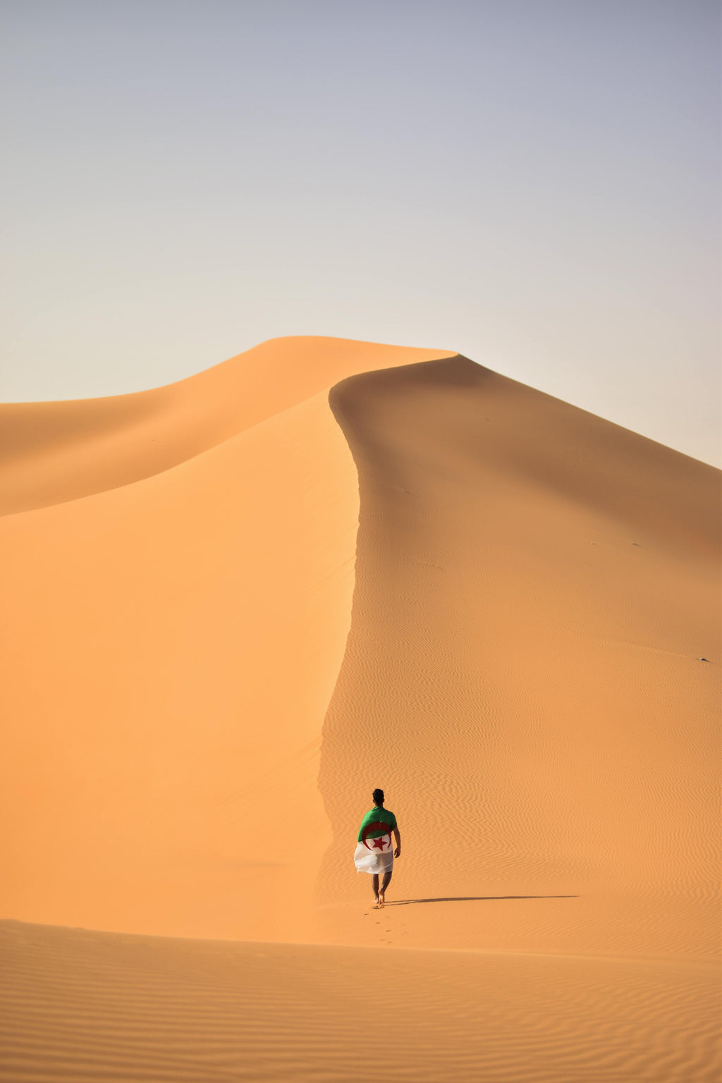Person walking alone on a sand dune in a wide desert landscape — a calm symbol of inner journey, self‑leadership, and essential clarity.