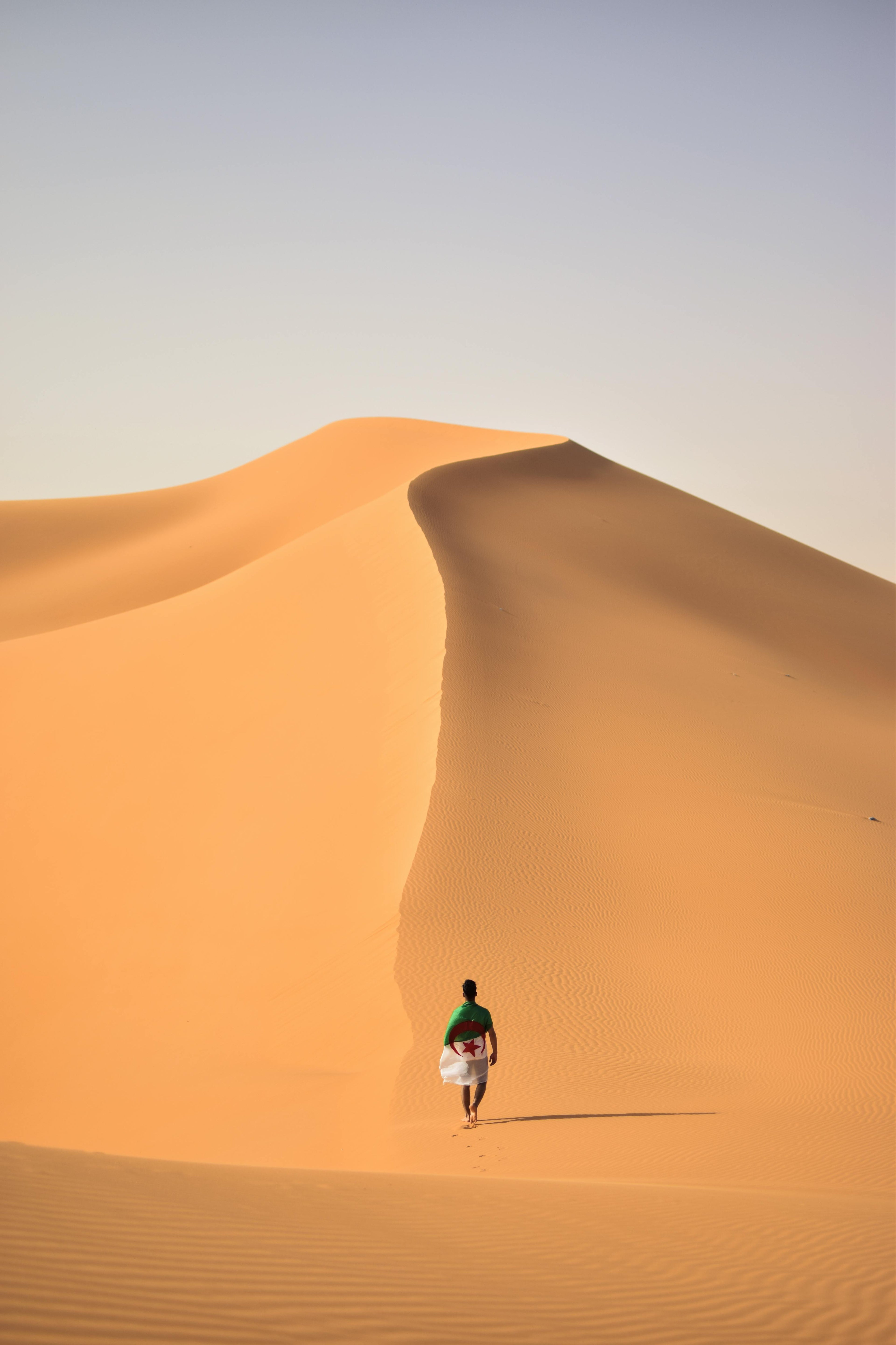 Person walking alone on a sand dune in a wide desert landscape — a calm symbol of inner journey, self‑leadership, and essential clarity.
