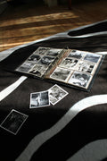 photo album resting on a soft carpet, with old photographs gently taken out and held for a closer look