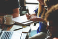 People sitting at a table with notebooks and a laptop, engaged in focused work — a calm symbol of collaboration, shared clarity, and collective intelligence.