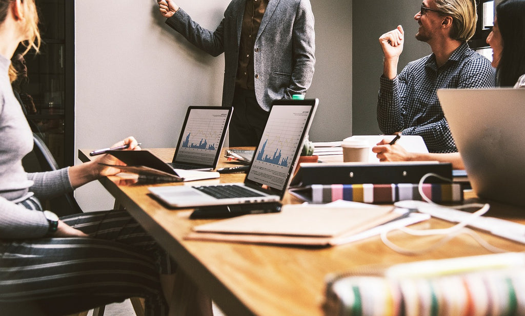 a group of people working on laptops at a wooden table in a modern office, focused on collaboration, leadership, and shared problem‑solving — a clean, calm workspace scene ideal for productivity and team dynamics.