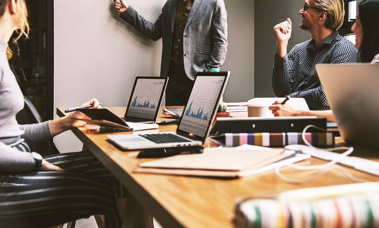 a group of people working on laptops at a wooden table in a modern office, focused on collaboration, leadership, and shared problem‑solving — a clean, calm workspace scene ideal for productivity and team dynamics.